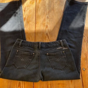 Lågmidjade svarta jeans - Jätte snygga lågmidjade jeans med snygga detaljer i gott skick! Obs de är svarta, solen gör att de ser ut att vara blå😊De är bootcut/raka
