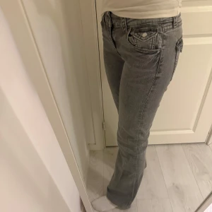 Grå jeans med bootcut - Snygga grå jeans med bootcut-stil och klassisk femficksdesign. De har en knapp och dragkedja framtill samt dekorativa sömmar på bakfickorna. De är från Gina Young i storlek 164
