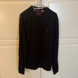 Svart långärmad tröja från Tommy Hilfiger Kashmir Blend - Snygg svart långärmad tröja från Tommy Hilfiger med en liten logotyp på bröstet. Perfekt för en stilren och avslappnad look. Tröjan har en rund halsringning och är tillverkad i ett mjukt material. Kashmir Blend. 