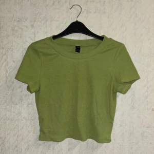 Grön ribbad topp - Den är lite nopprig. Säljer en grön ribbad topp. Den har en croppad passform och korta ärmar. Toppen är i ett mjukt och bekvämt material.