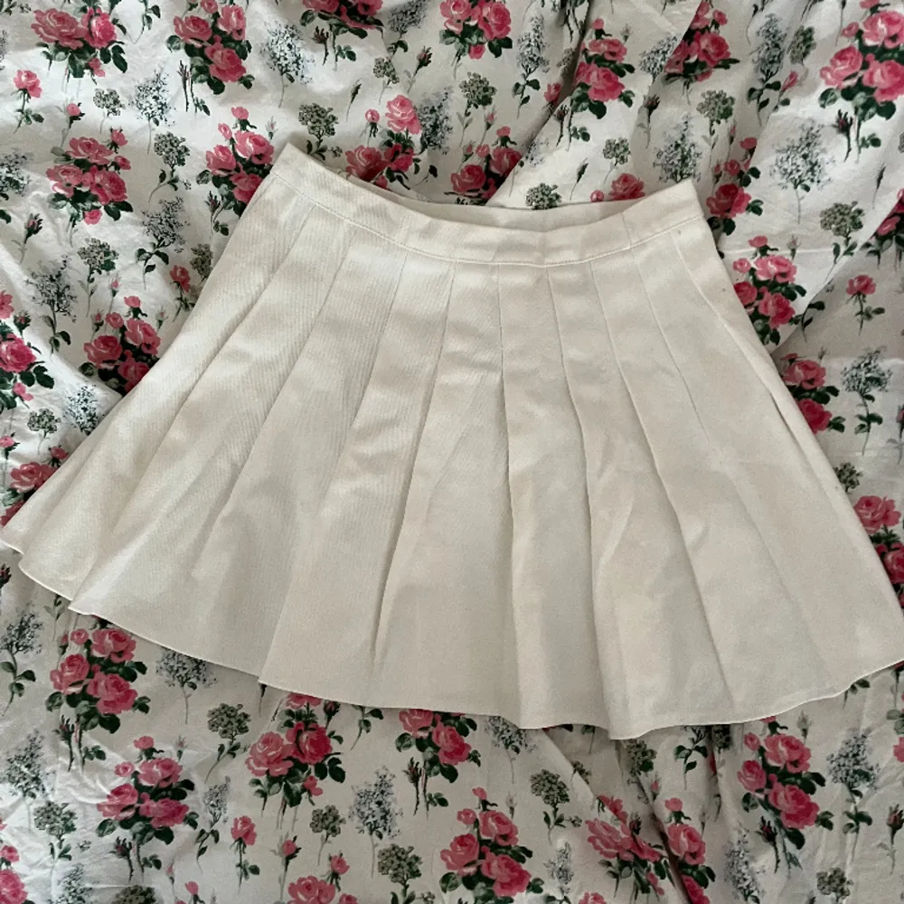 En cremevit kort veckad plisserad kjol med hög midja i jeansliknande material i strl M, men skulle mer säga strl S!💓. Hameet.