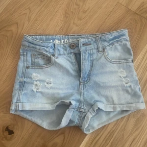 Ljusa jeansshorts från Lab Industries - Snygga ljusa jeansshorts från Lab Industries med slitna detaljer framtill. Storleken säger 146 men jag som har storlek 158 får på mig dom så dom är ganska stora i storlek!