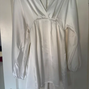 Vit klänning från Gina Tricot - Elegant vit klänning från Gina Tricot i satin med långa ärmar och v-ringning!