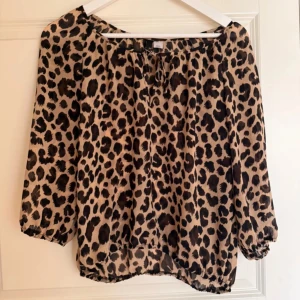 Leopardmönstrad blus - Snygg leopardmönstrad blus med trekvartsärmar och knytning vid halsen. Perfekt för att ge en vild touch till din outfit. Blusen har en luftig passform och är gjord i ett lätt material.