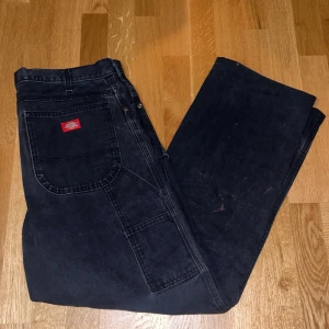 Svarta byxor från Dickies - Säljer ett par svarta vintage byxor från Dickies med en klassisk design. Byxorna har en lös passform och fläckarna är en del av designen.