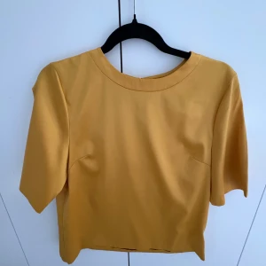 Gul topp från Stylein - Säljer en stilren gul topp från Stylein i storlek M. Toppen har en enkel design med korta ärmar och en rund halsringning. Perfekt för en färgglad touch i garderoben.