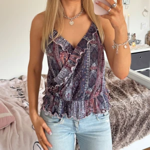 Mönstrad omlottopp med volang - Säljer en snygg mönstrad omlottopp med volangdetaljer. Toppen har smala axelband och en elastisk midja för en bekväm passform. Perfekt för en somrig look! ⊹ jag är 173cm & stl S/36/28 för referens ⊹ läs POLICY (i gillade inlägg) innan köp ⊹ använd gärna ”Köp” ⊹ 