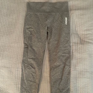 Grå leggings från Gymshark - Snygga grå leggings från Gymshark med hög midja och en bekväm passform. Perfekta för träning eller en avslappnad dag. Materialet är stretchigt och följsamt.