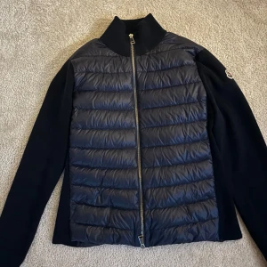 Marinblå Moncler cardigan  - Snygg marinblå cardigan från Moncler med quiltad framsida och dragkedja. Den har bra skick (använd ca 4 ggr) men köpte för runt 2 år sedan. Pris kan diskuteras, skriv vad ni kan ge för den!