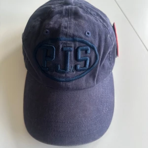 Mörkblå keps från Parajumpers - Snygg mörkblå keps från Parajumpers med broderad logga framtill och ett färgglatt märke på sidan. Kepsen har justerbar rem baktill för perfekt passform.