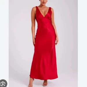 Röd balklänning - Snygg röd lång balklänning med djup v-ringning och ärmlös design. Perfekt för en elegant kväll. Klänningen har en smickrande passform och är tillverkad i ett glänsande material.