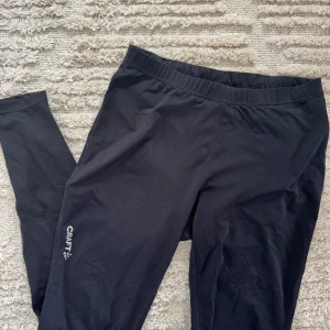 Svarta träningstights från Craft - Säljer ett par svarta träningstights från Craft. De är designade för optimal rörelsefrihet och komfort under träning. Perfekta för gymmet eller löprundan. Snörning på insidan i midjan för att kunna hålla dem på plats 