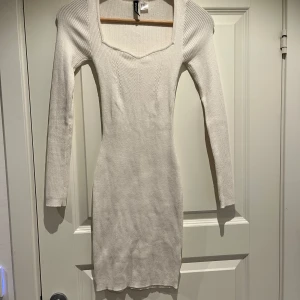 Vit ribbad klänning  - Säljer en stilren vit ribbad klänning. Klänningen har en tight passform och långa ärmar, perfekt för en elegant look. Den är tillverkad i ett mjukt material som känns skönt mot huden. Bara använd en gång.