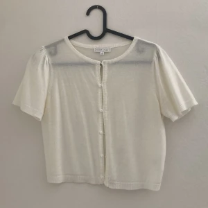 Vit kofta från Emory Park - Säljer en söt vit kofta från Emory Park. Den har korta ärmar och knappar framtill. Perfekt för lager-på-lager och att ha över en topp eller klänning. Enkel och stilren design som passar till många tillfällen. Storlek M men mer som en S i storlek. 