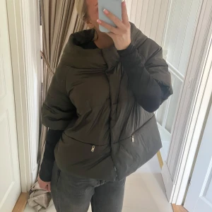 Olivgrön pufferjacka med dragkedja - Säljer min fina olivgröna pufferjacka med unik design. Jackan har en oversized passform med trekvarts  ärmar. Perfekt för vår/sommar!🩷