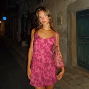 Rosa blommig klänning - Säljer en söt rosa klänning med blommigt mönster. Klänningen är ärmlös och har smala axelband som knyts. Perfekt för varma sommardagar eller en kväll ute. 💖