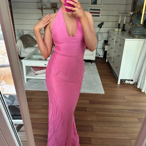 Rosa långklänning från Adoore  - Säljer en snygg rosa långklänning från Adoore med djup v-ringning och öppen rygg. Klänningen har en elegant passform och knytning i nacken. Perfekt för sommarens fester eller studentbal💖☀️🌻❤️