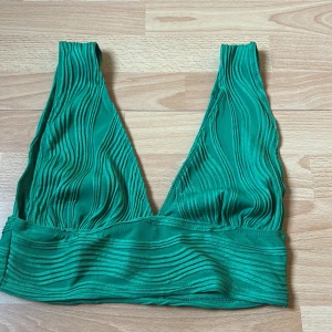 Grön ribbad topp från Shein - Säljer en snygg grön ribbad topp från Shein. Toppen har en djup v-ringning och breda axelband. Perfekt för en trendig look. Passar bra till både jeans och kjol. 🌿