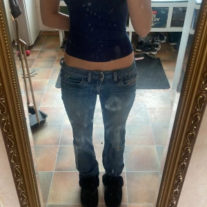 Blå jeans från Diesel - Snygga blå jeans från Diesel med en klassisk femficksdesign och slitna detaljer benen. De har en knappgylf och är i en bootcut modell. Jag säljer bara för att jag redan har flera andra jeans i samma färg så det är absolut inget fel på de här de är jättefina skulle även säga att de är små i storleken jag brukar i vanliga fall ha w25 men de här passar jättebra och de är ju i storlek w28