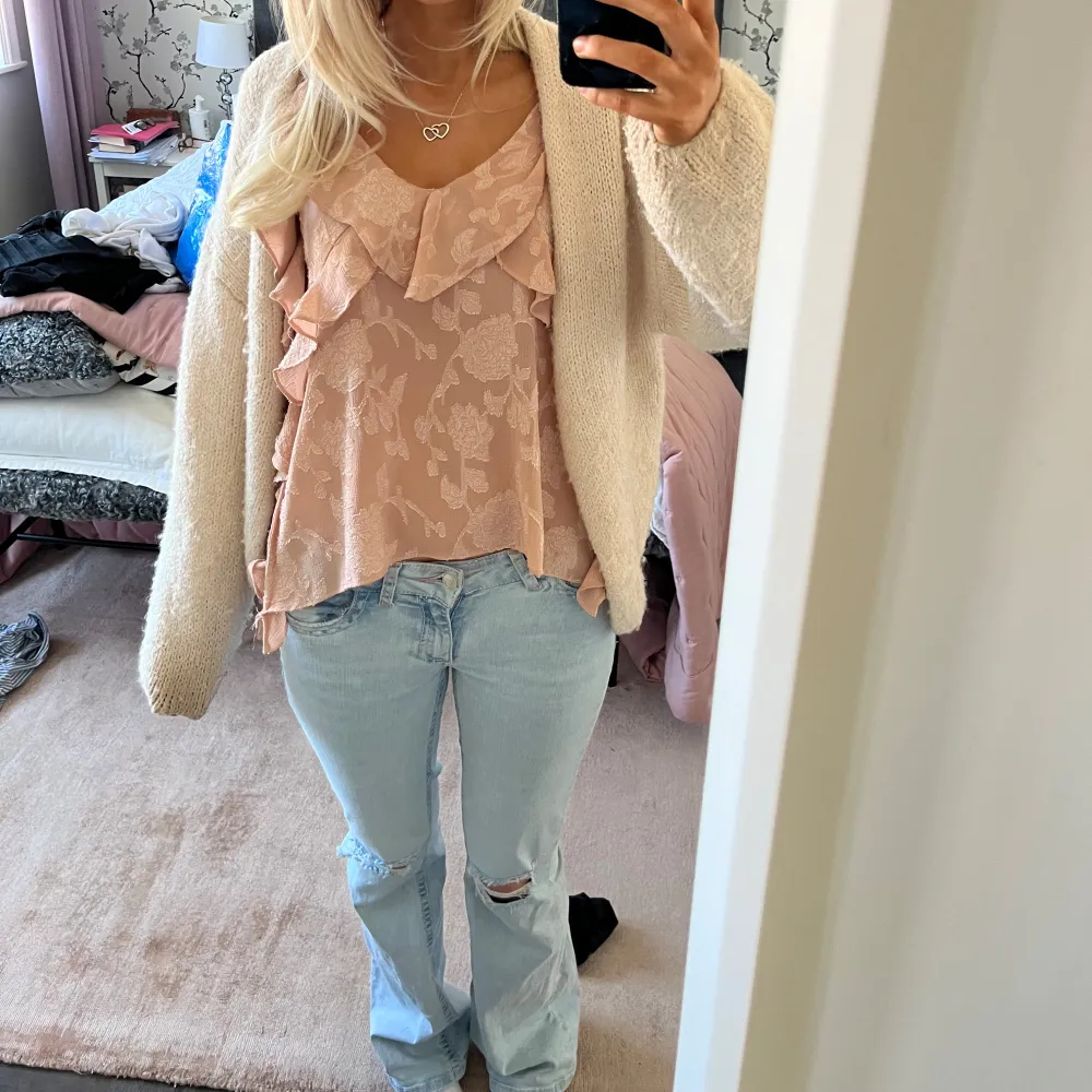 Säljer en söt rosa linnetopp med blommigt mönster och volangdetaljer. Toppen är ärmlös och har en luftig passform, perfekt för varma dagar. Den har smala axelband och en vacker volangkant. Helt slutsåld. Yläosat.