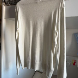 Vit turtleneck tröja - Säljer en stilren vit turtleneck med långa ärmar. Perfekt för kyligare dagar och enkel att matcha med olika outfits. Tröjan har en klassisk design med ribbade kanter vid ärmslut och nederkant.