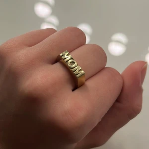 Guld MOM ring från Edblad XS - Snygg guldfärgad ring med texten 'MOM' i stora bokstäver. Perfekt som en personlig present eller för att visa uppskattning. Ringen har en modern och stilren design. Skriv för egna bilder❤️❤️Orginal pris - 399kr