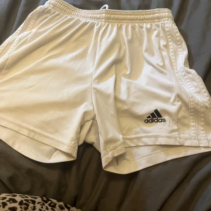 Vita träningsshorts från Adidas - Säljer ett par vita träningsshorts från Adidas med elastisk midja och logga på benet. Perfekta för sport och träning med en bekväm passform. 🏃‍♂️säljer båda för 100kr eller 70kr/st båda är det S på