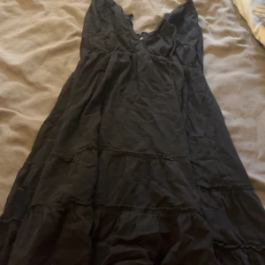 Svart klänning från Shein - Snygg svart klänning från Shein med v-ringning och volangdetaljer. Perfekt för en stilren look. Klänningen har en luftig passform och är tillverkad i ett lätt material.