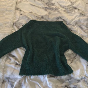 Mörkgrön stickad tröja från Holly & Whyte - Säljer en mysig mörkgrön offshoulder stickad tröja från Holly & Whyte by Lindex. Tröjan har en enkel design med långa ärmar och ribbstickade kanter. Perfekt för kyliga dagar!