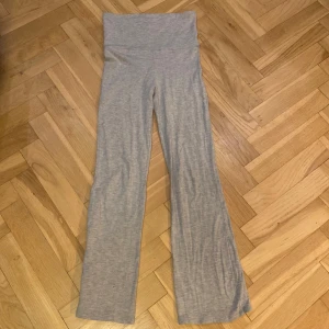 Grå byxor från Gina Tricot - Säljer ett par grå byxor från Gina Tricot. De är tillverkade i ett mjukt material och har en hög midja. Byxorna har en rak och avslappnad passform, perfekt för en bekväm stil.