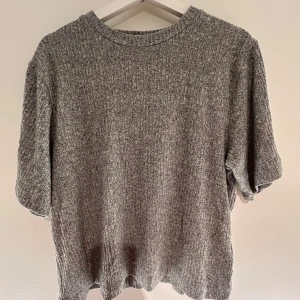 Grå ribbad tröja från 57 - Säljer en stilren grå ribbad tröja från märket 57. Tröjan har en normal passform och korta ärmar, perfekt för en avslappnad look. Den är tillverkad i ett mjukt material som ger en skön känsla mot huden. Kontakta mig om det är något. Köparen står för frakten💗