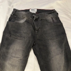 Grå jeans från BDG Urban Outfitters - Säljer ett par grå jeans från BDG Urban Outfitters med snygga kontrastsömmar och stora fickor både fram och bak. Jeansen är flare och coolt tvättad look. Perfekta för dig som gillar streetstyle och vill ha något unikt i garderoben.