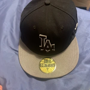 LA Dodgers keps New Era 59FIFTY svart/grå - Snygg LA Dodgers keps från New Era 59FIFTY-serien. Kepsen är svart med grå skärm och har broderad LA-logga framtill samt MLB-logga bak. Tillverkad i 100% bomull och har klassisk flat brim. Perfekt för dig som gillar streetstyle och sport.