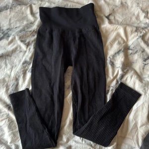 Svarta ribbade leggings XXS från Aim'n - Svarta ribbade leggings från Aim'n i storlek XXS. Hög midja och stretchigt material med 92% polyamid och 8% elastan. Diskret Aim'n-logga framtill. Perfekta för träning eller chill, sitter tajt och bekvämt.