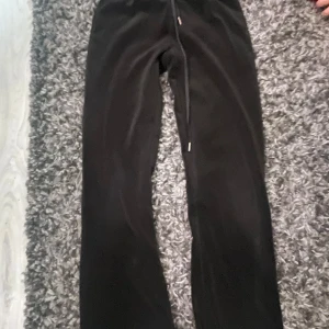 Svarta mjukisbyxor från Gina Tricot XXS - Svarta mjukisbyxor från Gina Tricot i storlek XXS. Byxorna har en rak passform med snörning i midjan och är gjorda i mjukt polyester- och elastanmaterial. Perfekta för chill dagar eller när du vill vara extra bekväm. Snygg enkel look och sköna att bära.