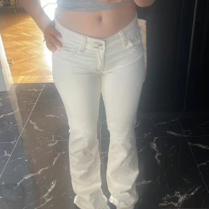 Vita bootcut jeans med hög midja - Snygga vita jeans med bootcut passform och hög midja. Klassisk femficksdesign med coola sömmar på bakfickorna. Jeansen har en stilren look och är tillverkade i mjukt denimtyg som sitter bekvämt. Perfekta för dig som vill ha en fräsch och trendig vibe.