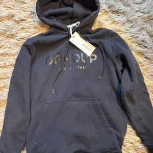 Blå hoodie från Dondup - Snygg svart hoodie från Dondup med tryckt logga på bröstet och klassisk känguruficka. Tröjan har huva med snörning och långa ärmar. Perfekt för en chill och stilren look.