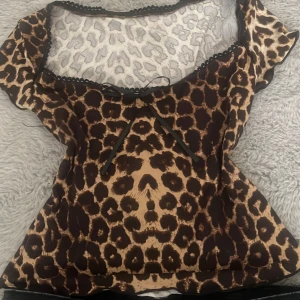 Leopardmönstrad blus med rosett - Snygg blus med leopardmönster i brunt och beige från shein. Toppen har korta ärmar, söt svart rosett framtill och vågig kant vid halsringningen. Tunt, lätt material som ger en luftig känsla och coolt intryck. Aldrig använt