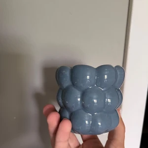 bubblig blå mini kruka - Bilderna visar en blå, bubblig keramikskål med unik form och glansig yta. Skålen har en modern och lekfull design som passar perfekt som inredningsdetalj 