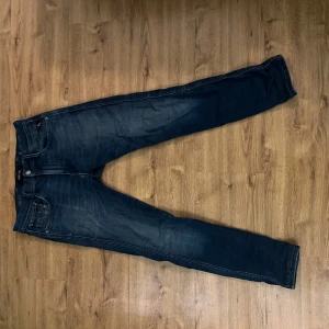 Replay Anbass Hyperflex - Upplev kombinationen av stil och komfort med dessa exklusiva Replay Anbass Hyperflex jeans. Storlek: 32/32 	•	Färg: Mörkblå med elegant tvätt och diskreta slitningar 	•	Modell: Slim fit – följer kroppens linjer på ett snyggt och bekvämt sätt  Skick: Mycket välvårdade. Finns en liten skavank vid sömmen (se bild) som är diskret och inte märks när jeansen används. Tänker sälja de för 399 men pris kan diskuteras vid snabb affär!🤩