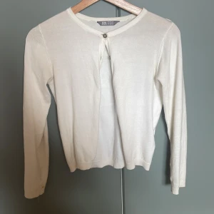 Vit kofta från Lindex Kids - Snygg vit kofta från Lindex Kids i storlek 146/152. Den har rund hals, långa ärmar och knappar framtill. Materialet är mjukt och stickat, perfekt för lager på lager. Enkel och clean design som funkar till många olika outfits. Den kan även passa folk som har xss eller xs då den kan vara lite tajt på ett snyggt sätt! 🌺🌺
