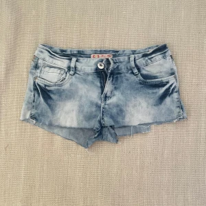 Lowwaist jeansshorts - ljusblå jeansshorts med detaljer på baksidan. strl M men ganska små i storleken så passar nog snarare S/XS. den har en liten ojämnhet på ena sidan men det är inget som syns