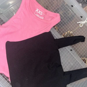 2 ribbade linnen från FSBN Sister & Amisu - Säljer två stilrena ribbade linnen: ett rosa från FSBN Sister i storlek XXS och ett svart från Amisu i storlek XS. Båda har ärmlös design och stretchigt material som sitter snyggt på kroppen. Perfekta att matcha med jeans eller kjol för en trendig look.