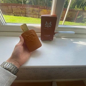 Parfums de Marly Althaïr  - Exklusiv parfym från Parfums de Marly, Althaïr Eau de Parfum i en snygg brun flaska med guldigt lock. Flaskan rymmer 110 ml och har en lyxig känsla med präglad logga framtill. Kommer i matchande brun kartong med silverdetaljer. Den är lite använd så det är runt 110 ml kvar jag tror att det är lite mer än det men är inte säker.