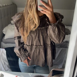 Brun blus från Object - Jättesöt brungrön blus från Object. Söta volangdetaljer kring axlarna och nedtill vid händerna. Säljer då den är lite för stor för mig. Orginalpris var 800kr. Klicka gärna på ”köp nu”!