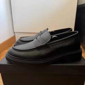 Massimo Dutti loafers i skinn - Snygga svarta loafers med stilren design och chunky sula. Gjorda i slätt skinn med rund tå och diskreta sömmar. Perfekta för dig som vill ha en clean och tidlös look till både jeans och kostym. Aldrig använda 