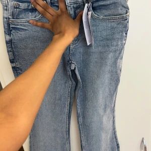 Ljusblå bootcut jeans storlek 38 - Snygga ljusblå jeans med bootcut-modell och klassisk femficksdesign. Jeansen har en lätt tvättad look och normal passform. Tillverkade i mjukt denimtyg som sitter skönt på kroppen. Perfekta för dig som gillar en avslappnad men trendig stil.