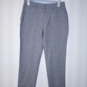 Grå linnebyxor från Dressmann - Snygga grå linnebyxor från Dressmann i mix av linne och bomull. Byxorna har klassisk passform med raka ben, bälteshällor och fickor både fram och bak. Perfekta för en chill och stilren look under varmare dagar.          Kan skickas med extra pris via post.