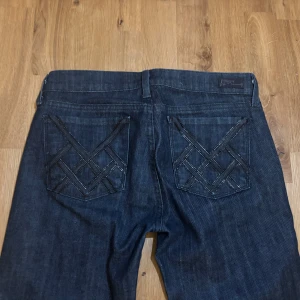 Mörkblå  bootcut jeans - Snygga mörkblå bootcut jeans från citizens of humanity med låg midja. Baksidan har coola detaljerade fickor med broderade mönster. Perfekta för dig som gillar en tidlös jeansstil med lite extra edge.