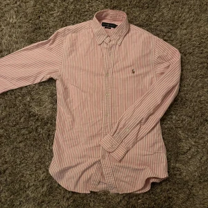 Rosa randig skjorta från Ralph Lauren🤩 - Säljer en slim fit skjorta från Ralph Lauren i rosa och vitt med klassiskt randigt mönster. Skjortan är i storlek S och pris går alltid att diskutera🤩🙌